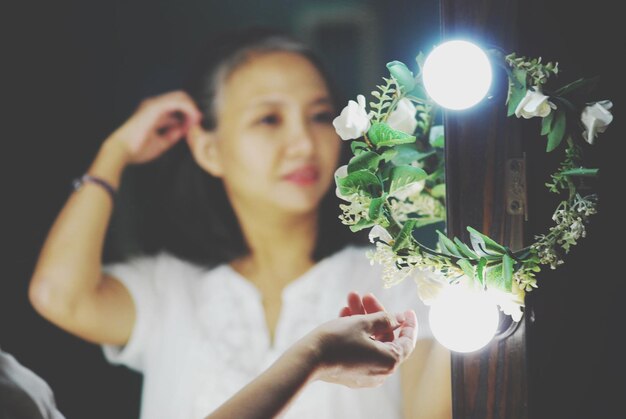 Foto mujer tocando la decoración iluminada mientras se refleja en el espejo