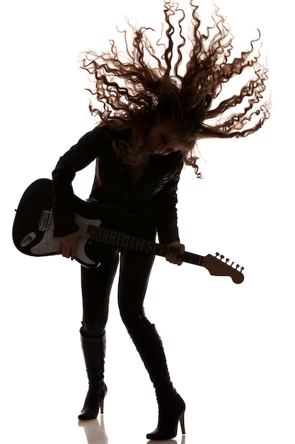 Mujer tocando la guitarra y bailando, agitando su cabello. Foto de cuerpo entero aislado sobre fondo blanco.