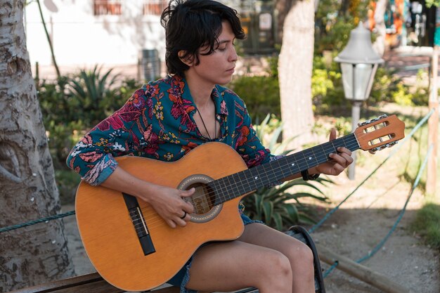 Mujer tocando la guitarra sentada en un parque