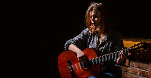 Mujer tocando la guitarra, sosteniendo una guitarra acústica en sus manos. Concepto de música. Toca el guitarrista de niña.