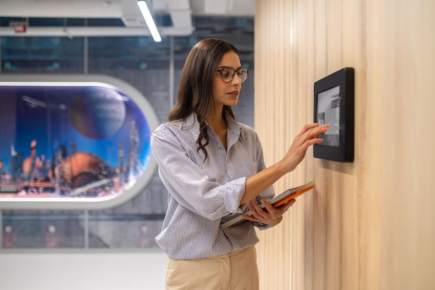 Mujer tocando el panel de control en la pared del corredor