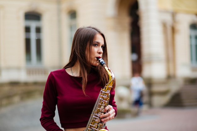 Mujer tocando el saxofón en las calles de la ciudad.