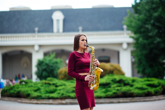 Mujer tocando el saxofón en las calles de la ciudad.