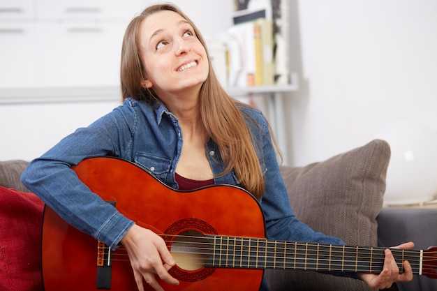 Mujer tocar la guitarra en casa