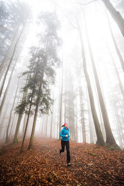 Foto mujer a toda longitud corriendo en el bosque durante el otoño