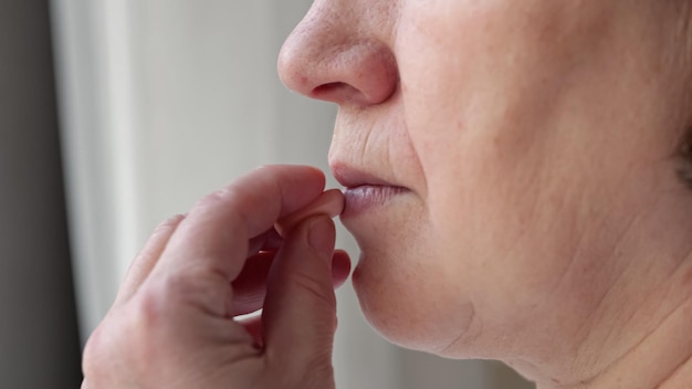 Mujer toma analgésicos para aliviar el dolor de cabeza bebiendo agua