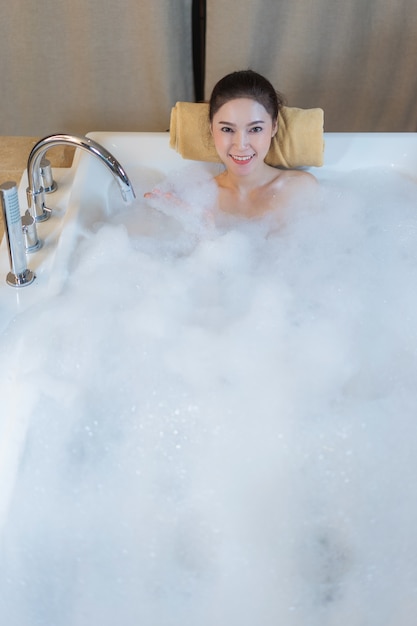 mujer toma baño de burbujas y jugando en la bañera