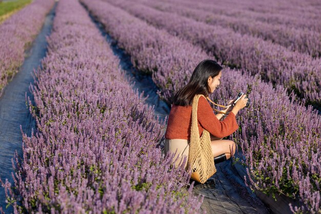 Una mujer toma una foto con una cámara digital en un campo de flores púrpuras