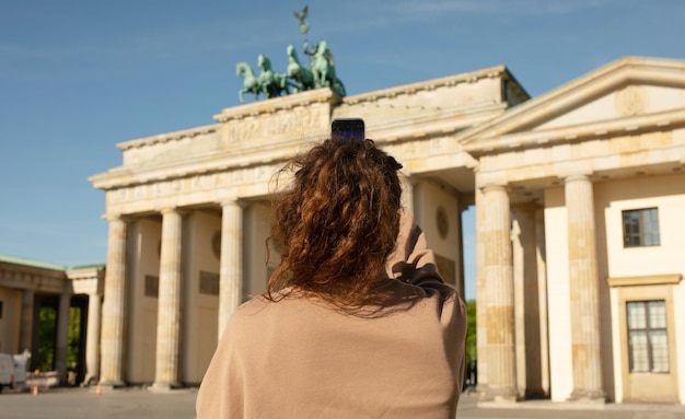 Una mujer toma una foto de la puerta de brandenburgo