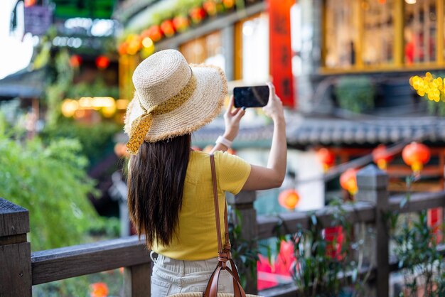 Una mujer toma una foto con su teléfono móvil en el pueblo de Jiufen, en Taiwán.