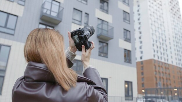 Una mujer toma fotografías de edificios con una cámara profesional y una hermosa fotógrafa dispara