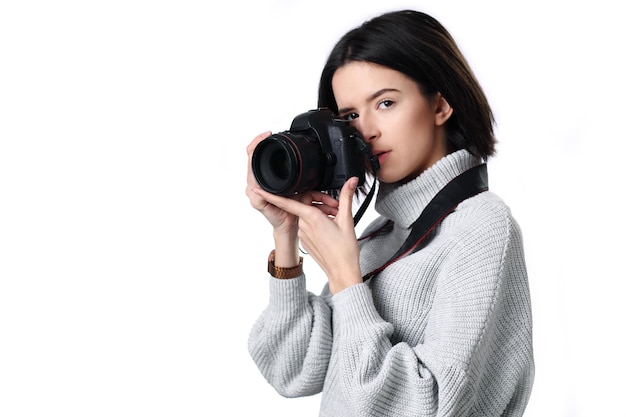 La mujer toma imágenes sosteniendo una cámara fotográfica aislada en un blanco