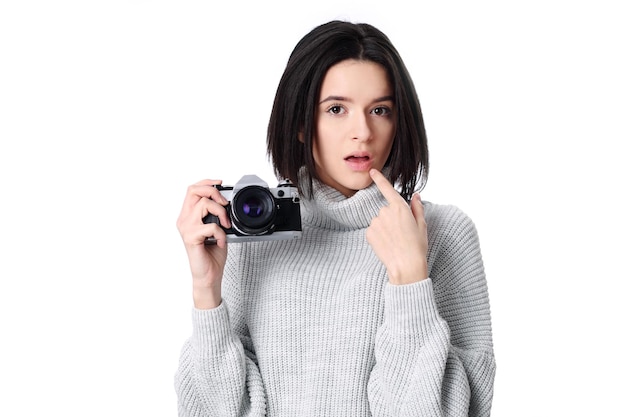 La mujer toma imágenes sosteniendo una cámara fotográfica aislada en un blanco