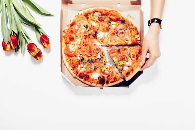 Mujer toma una porción de pizza de la mesa