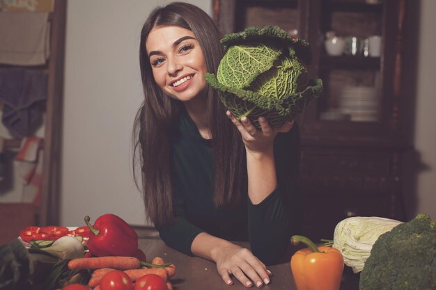 Foto la mujer toma un repollo en la mano en la mesa