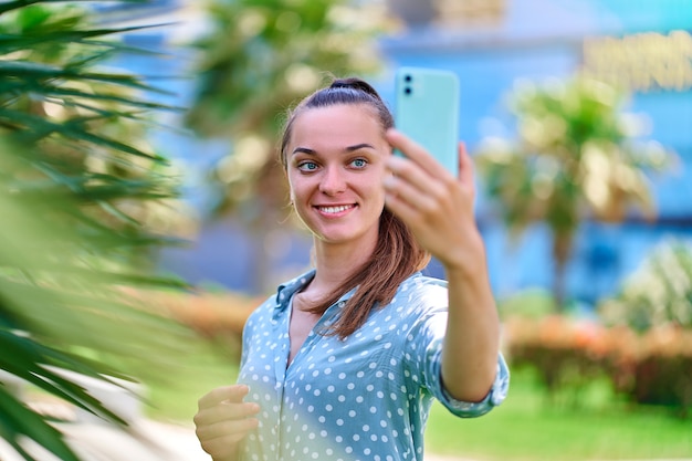 Mujer toma un retrato selfie en smartphone al aire libre