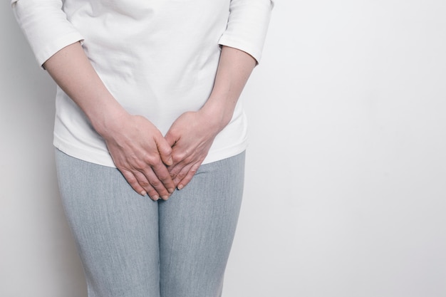 Una mujer toma sus manos por una entrepierna dolorida. Problemas ginecológicos en la parte baja del abdomen. Inflamación de la vejiga.