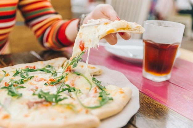 Mujer toma un trozo de pizza de cerca el enfoque suave