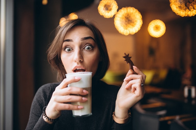 Mujer tomando café con estrella de galleta en un café