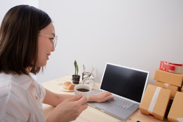 Mujer tomando café mientras trabajaba en la computadora portátil