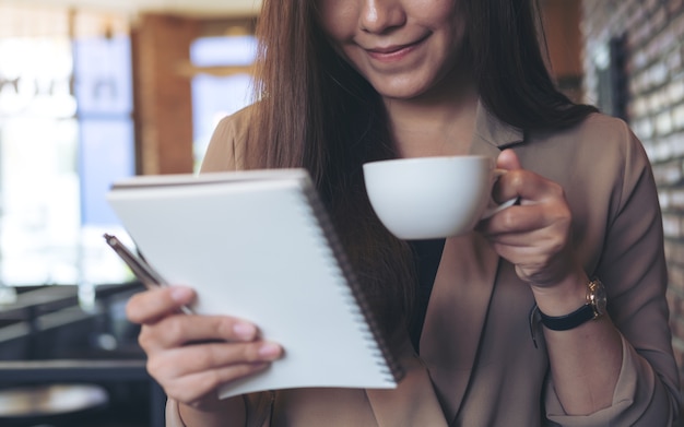 mujer tomando café y mirando un cuaderno