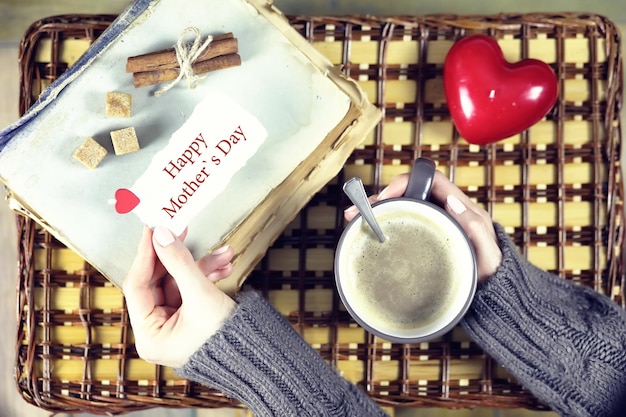 Mujer tomando café y mirando la tarjeta del día de la madre