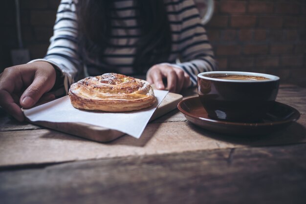 mujer tomando café con un pedazo de postre danés pasas