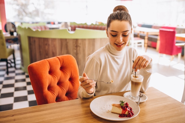 Mujer tomando café con postre en un café