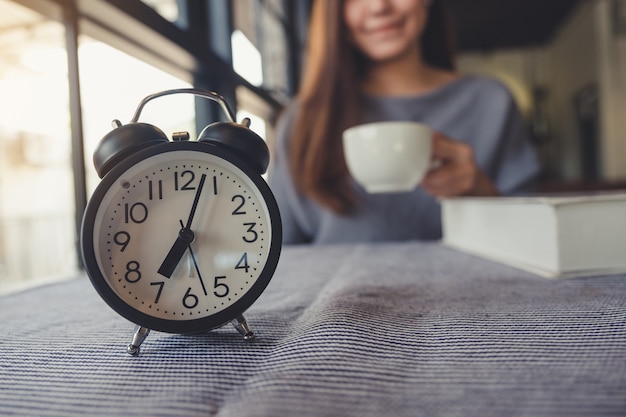 Foto mujer tomando café con reloj despertador