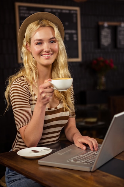 Mujer tomando café y usando laptop