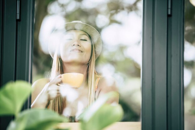 Foto mujer tomando café vista a través de una ventana de vidrio