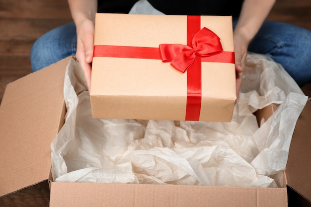 Mujer tomando caja de regalo de paquete en el interior