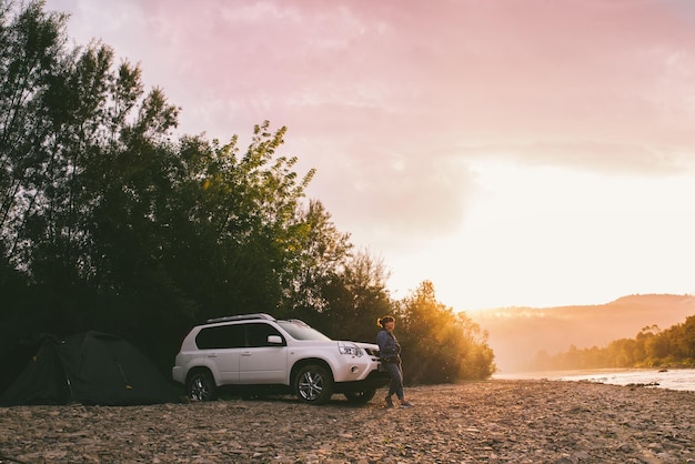 Mujer tomando una foto del amanecer en su auto teléfono acampando