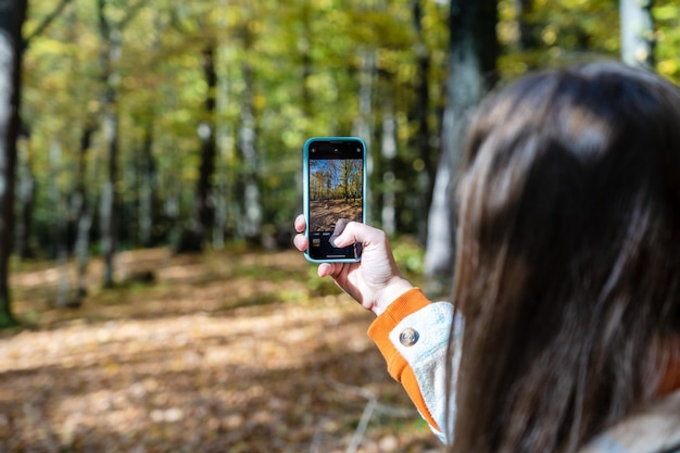 Mujer tomando una foto del bosque en otoño