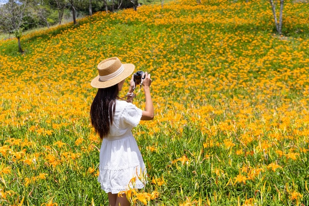 Foto mujer tomando una foto en el campo de flores de lirio en la montaña taimali kinchen en taitung de taiwán