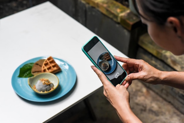 Una mujer tomando una foto de un helado para publicidad y redes sociales