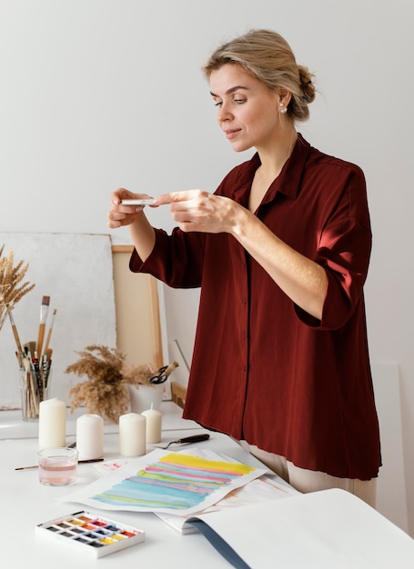 Foto mujer tomando una foto de su arte con su teléfono