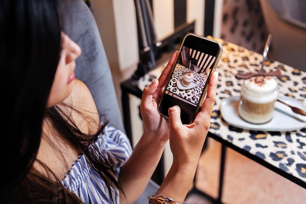 Mujer tomando una foto de su café con su teléfono
