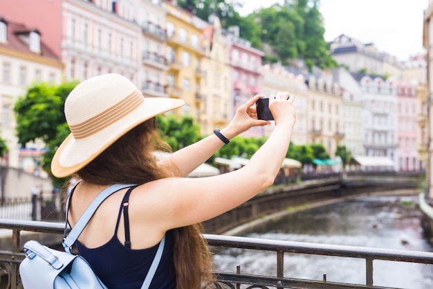 Mujer tomando fotografías con smartphone elegante viajero de verano mujer con sombrero con cámara al aire libre en