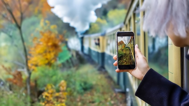 Mujer tomando fotografías del tren de vapor en movimiento Mocanita desde su interior, Rumania