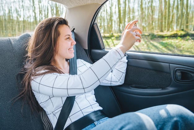 Mujer tomando fotos desde el asiento trasero del concepto de viaje en automóvil