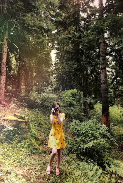 Foto mujer tomando fotos con un cañón en el bosque