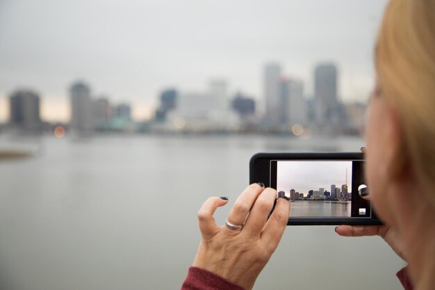 Mujer tomando fotos del horizonte de Nueva Orleans con su teléfono inteligente