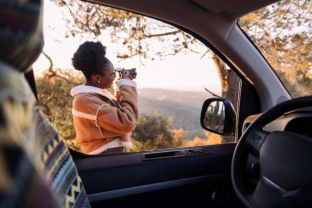 Mujer tomando fotos de la naturaleza durante un viaje por carretera