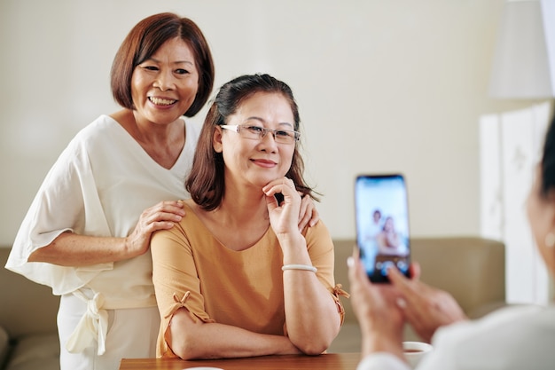 Mujer tomando fotos de sus amigas ancianas muy sonrientes