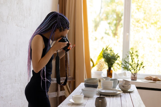 Mujer tomando fotos de utensilios de cocina de cerámica en casa