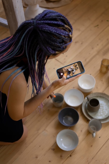Mujer tomando fotos de utensilios de cocina de cerámica en casa