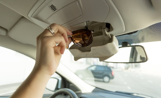 Mujer tomando gafas de sol del compartimento especial del coche