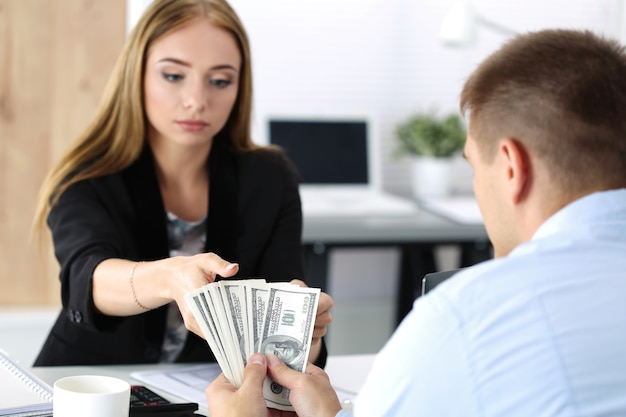 Mujer tomando lote de billetes de cien dólares. Venalidad, soborno, concepto de corrupción