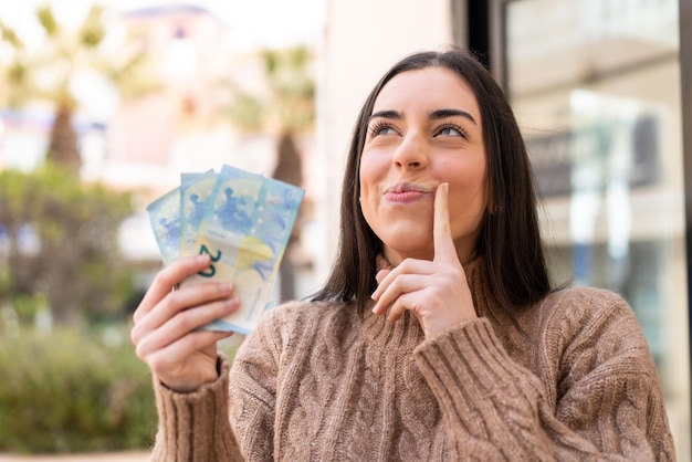 Mujer tomando mucho dinero al aire libre